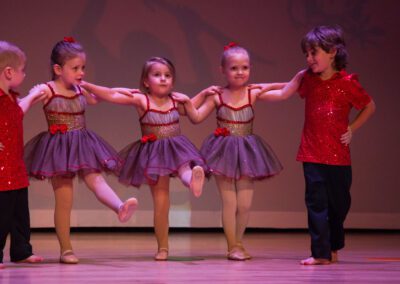 A group of young children wearing pink and blue outfits, standing together.